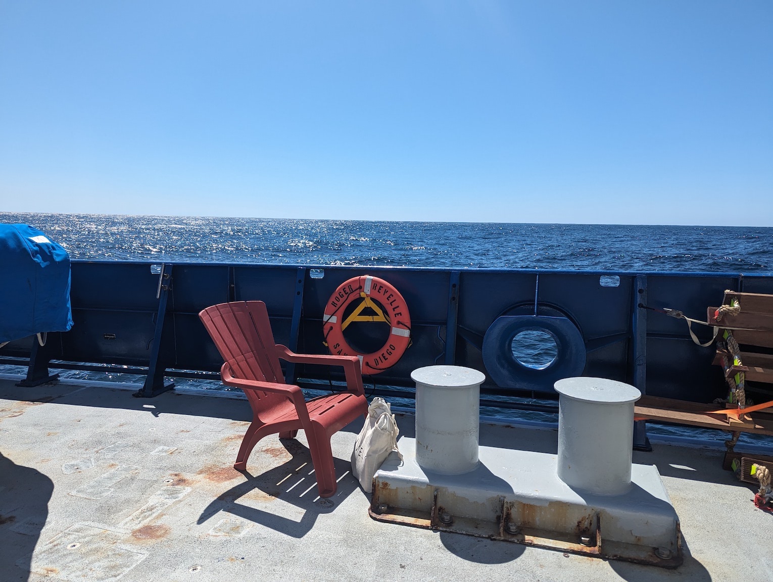 a red adirondack chair on deck, with the ocean in the background