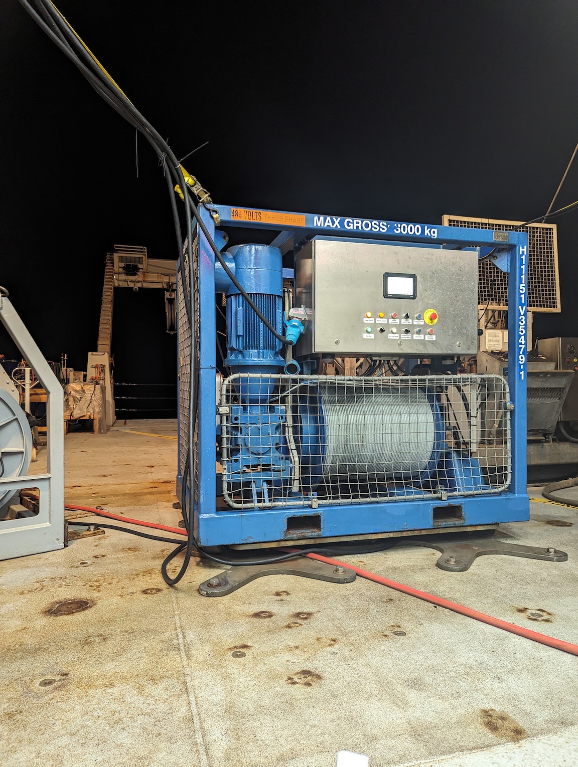 a blue winch in the foreground, bolted to the deck of the ship. Assorted other equipment in the background