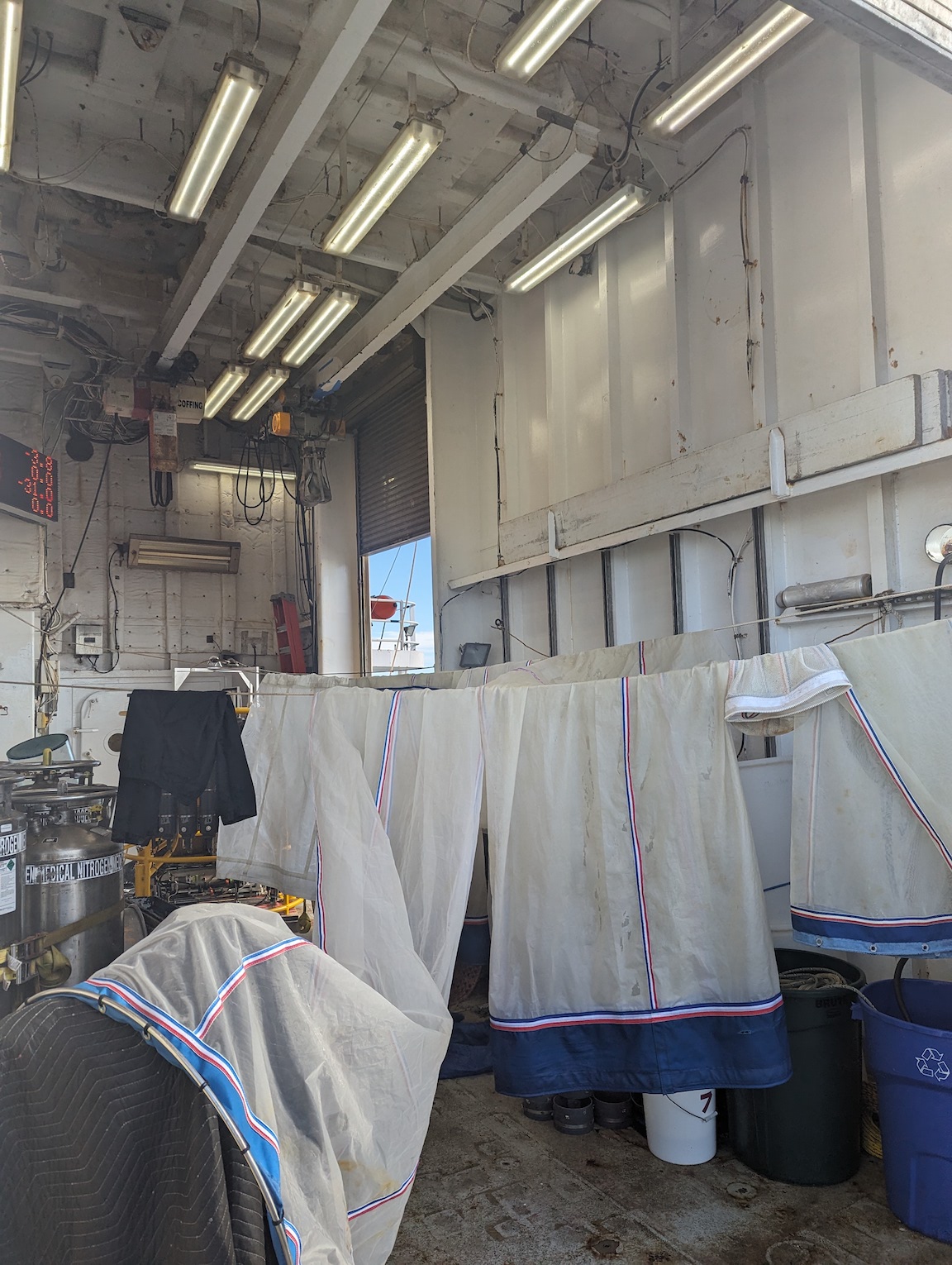 many nets crowded into the hangar to dry, amidst a bunch of other equipment that is partially packed