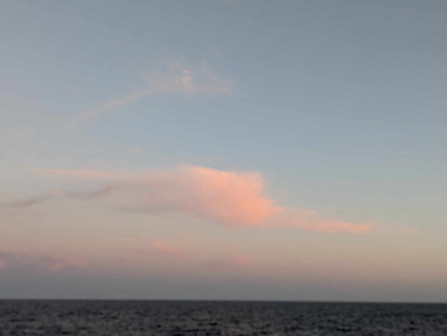 pastel colored cloud at sunset, over the ocean. Photo is slightly blurry