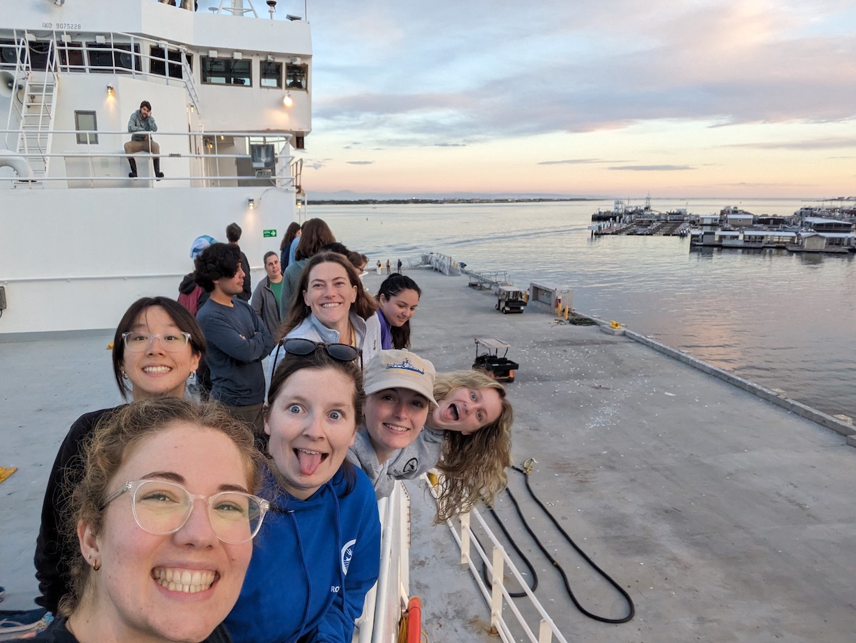 group photo of several people on deck, with sunset in the background