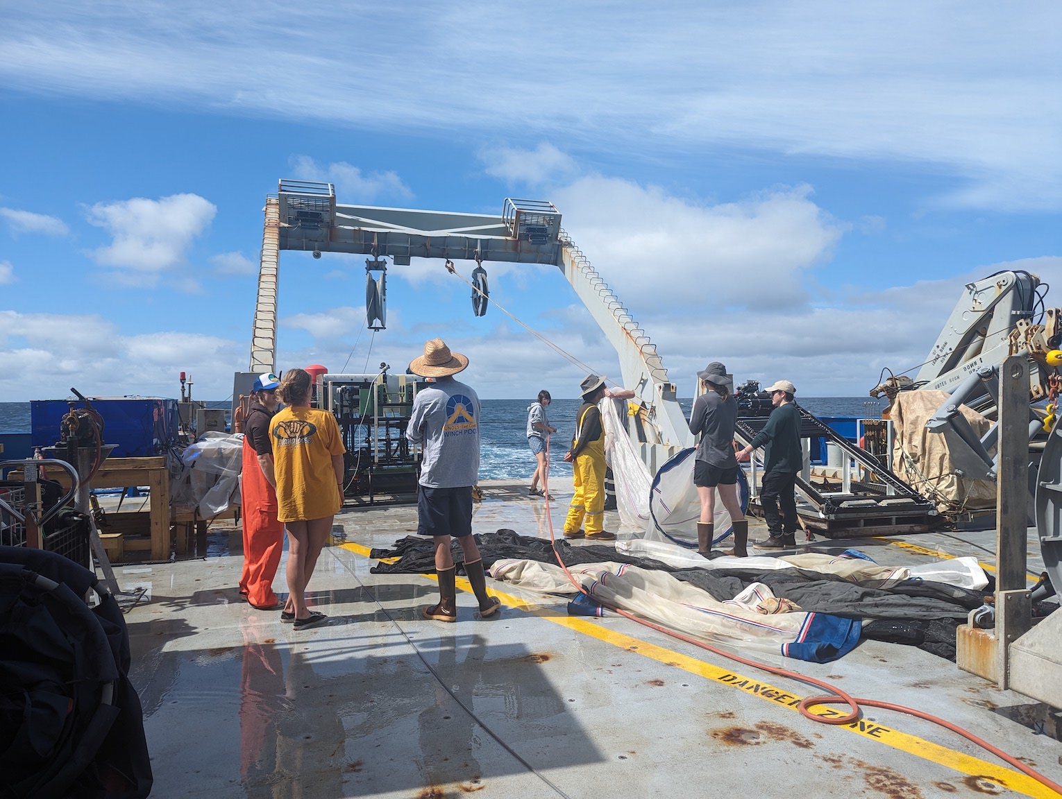 several people stand on aft deck, hosing off nets