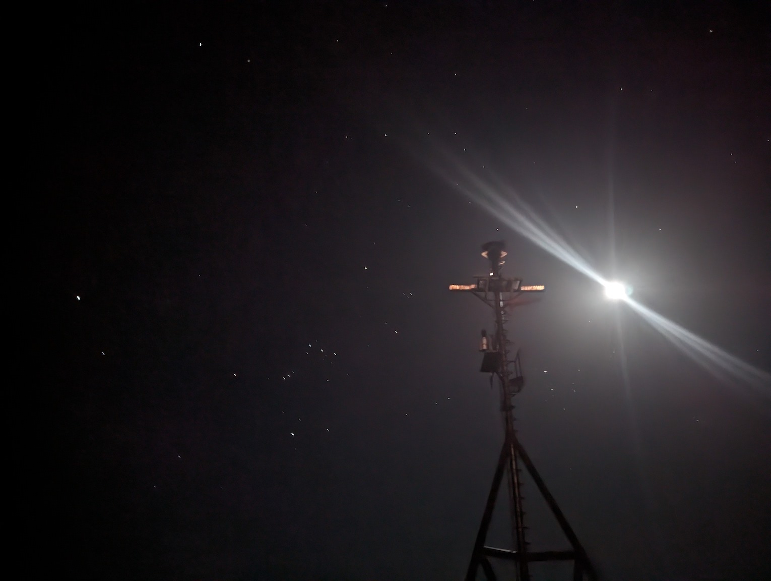 a dark photo, with some pinpricks of light (stars) and one very bright light (moon)