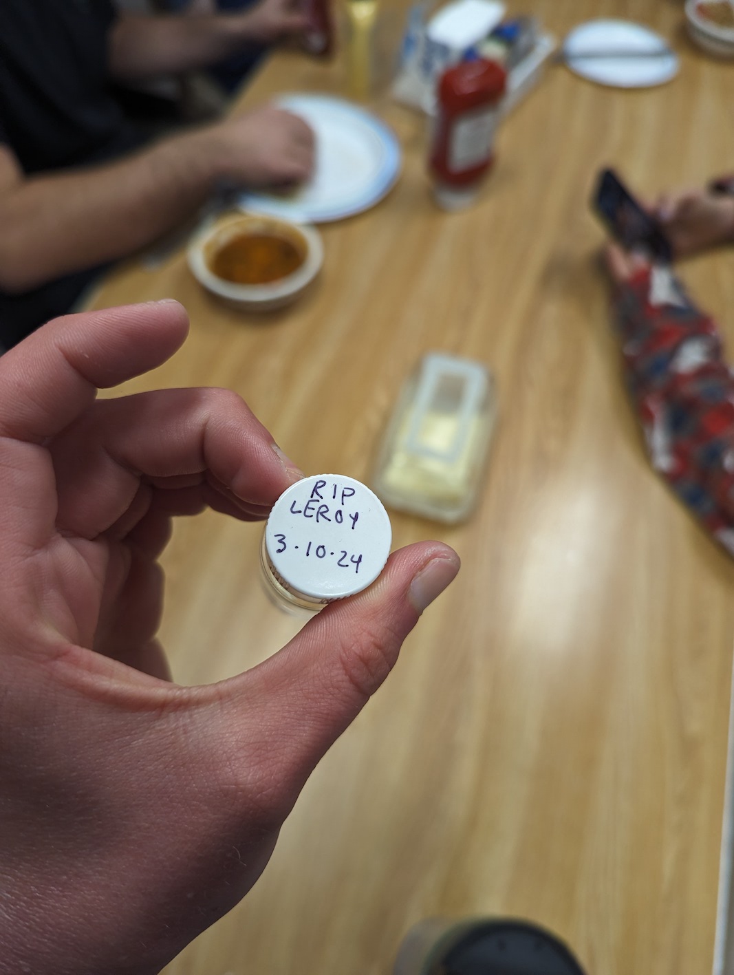 A small jar in the foreground with a table of people sitting in the background