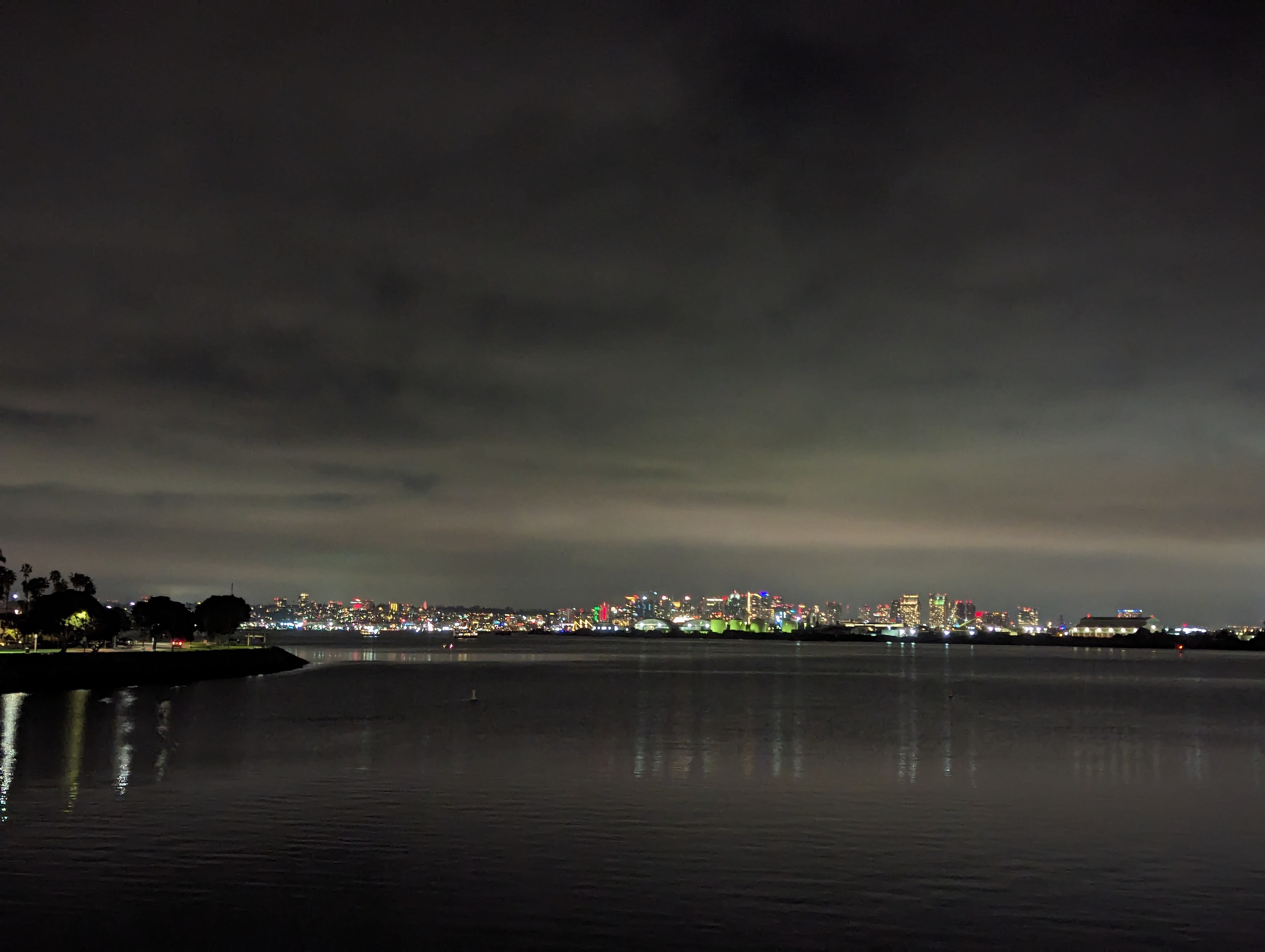 Night image of city skyline in the distance, across the water.