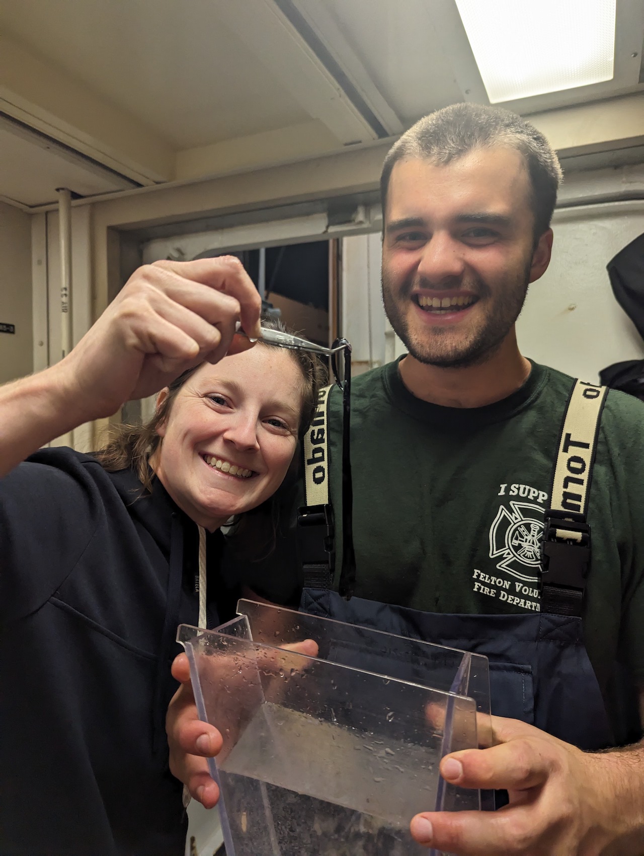 grace holding up a sea fish/snake. Sam holding a tub of water.