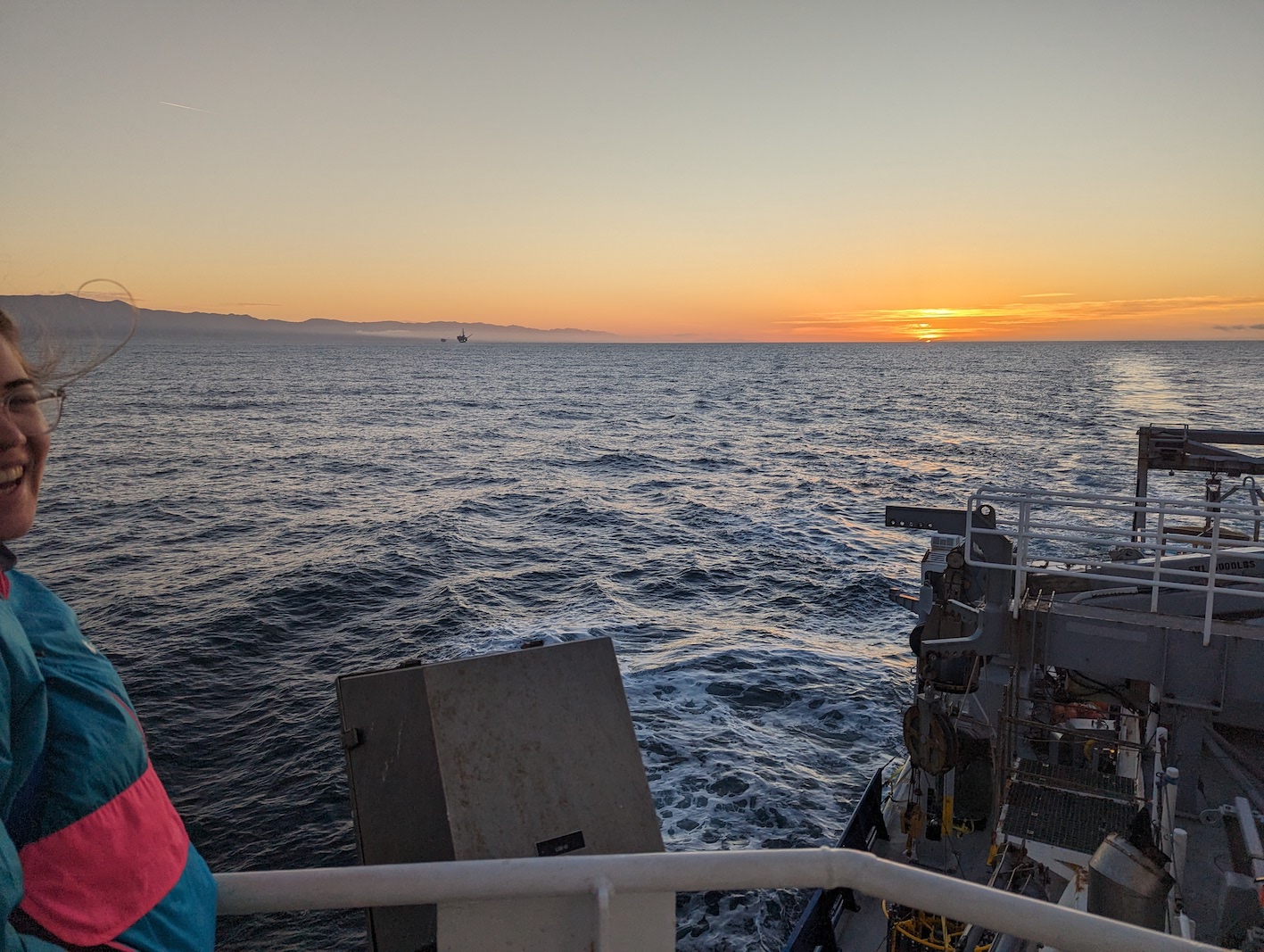 caro on the left corner looking out over the ship and the sun rising over the ocean.