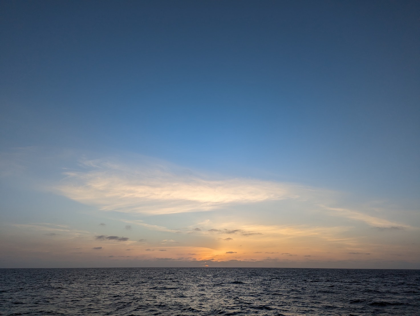 sunset over the ocean with streaky clouds