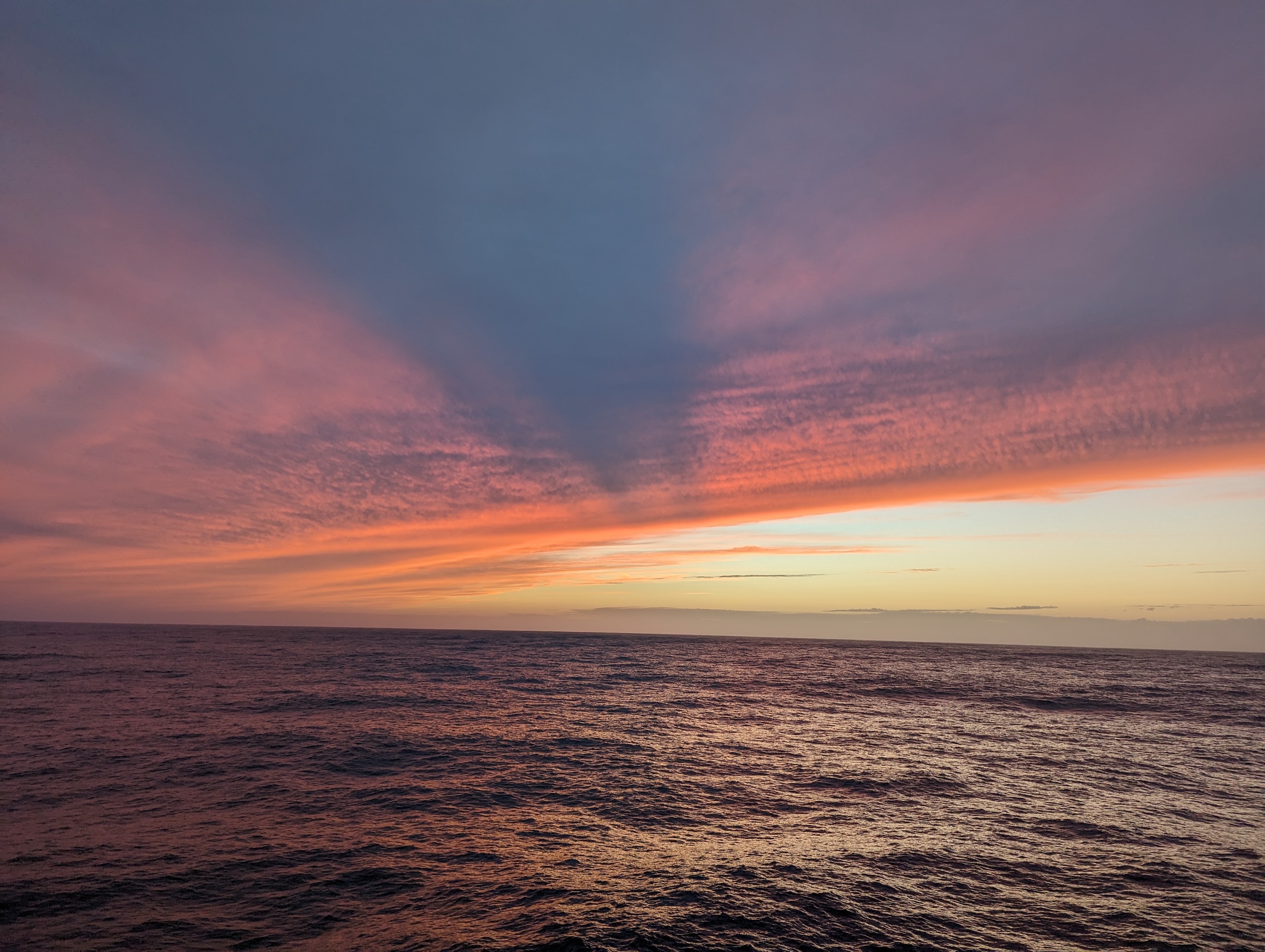 image of sunset over the ocean, with streaky clouds.