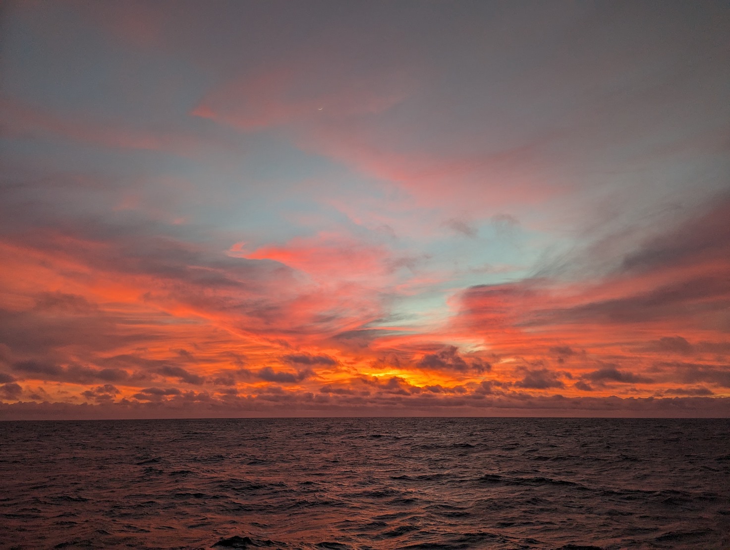 a stunning, multi-color sunset with lots of reds and golds. clouds lit up, over the pacific ocean