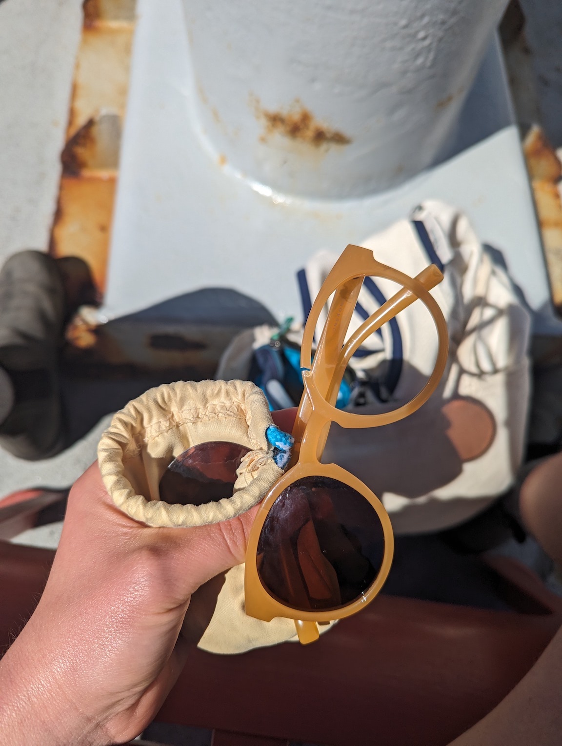 hand holding broken pair of sunglasses missing one lens